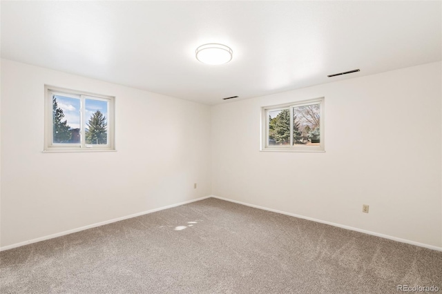 carpeted empty room with visible vents, plenty of natural light, and baseboards