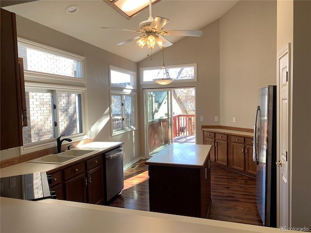 kitchen with stainless steel appliances, a kitchen island, sink, and dark wood-type flooring