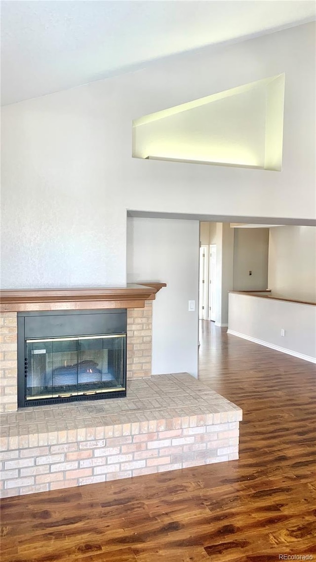 unfurnished living room featuring dark hardwood / wood-style floors and a brick fireplace