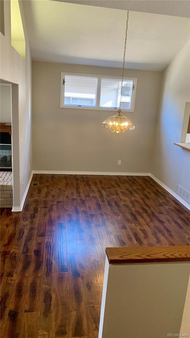 unfurnished dining area with an inviting chandelier and dark hardwood / wood-style floors