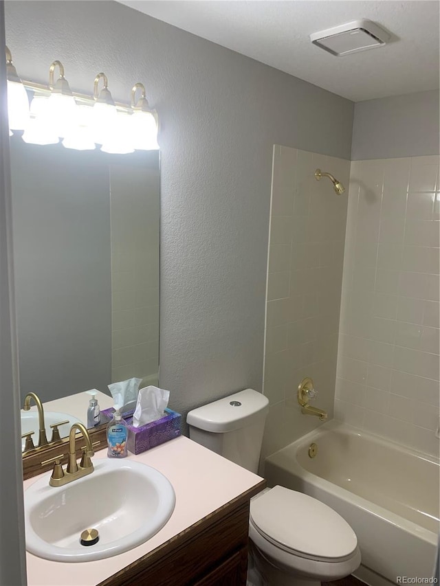 full bathroom featuring tiled shower / bath, vanity, and toilet