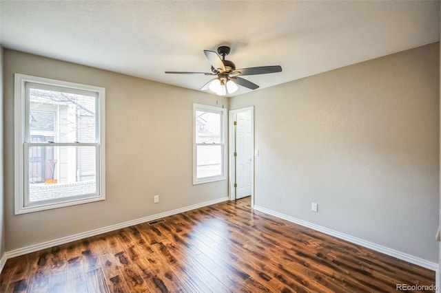 empty room featuring visible vents, baseboards, a ceiling fan, and dark wood-style flooring