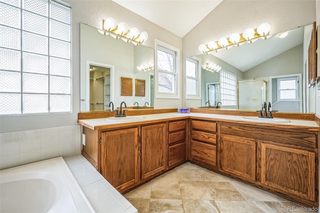 full bathroom with a wealth of natural light, a sink, and vaulted ceiling