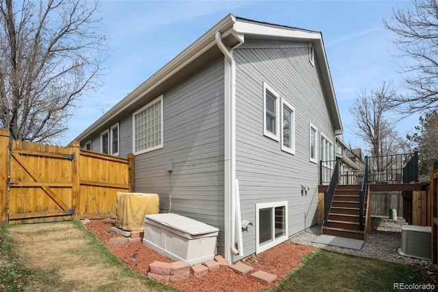 view of property exterior featuring a deck, stairway, a gate, and fence