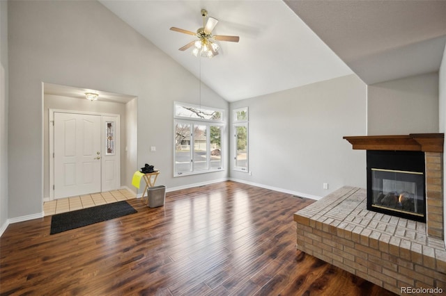 living area featuring high vaulted ceiling, a ceiling fan, wood finished floors, baseboards, and a brick fireplace