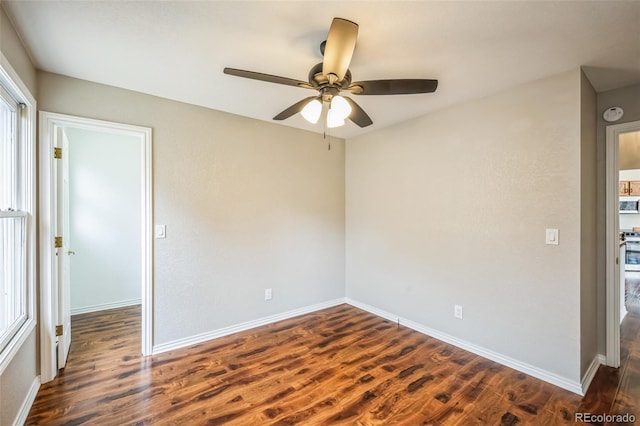spare room with dark wood finished floors, baseboards, and ceiling fan