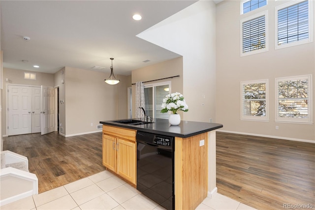 kitchen with sink, hanging light fixtures, light brown cabinets, black dishwasher, and an island with sink