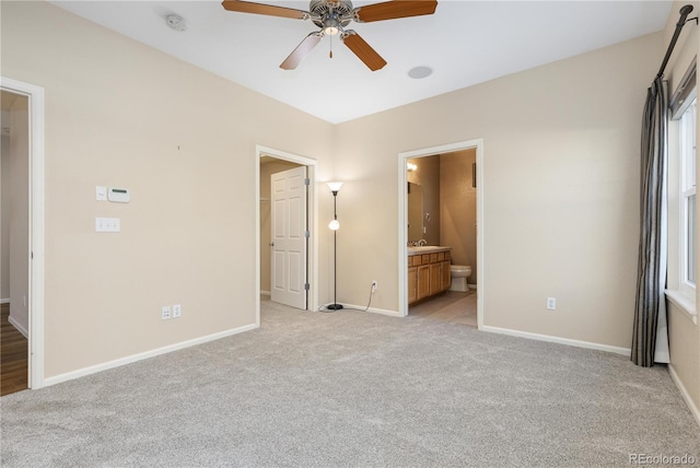 unfurnished bedroom featuring ceiling fan, ensuite bath, and light colored carpet