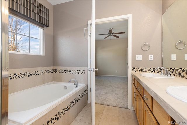 bathroom with tile patterned flooring, vanity, a relaxing tiled tub, and ceiling fan