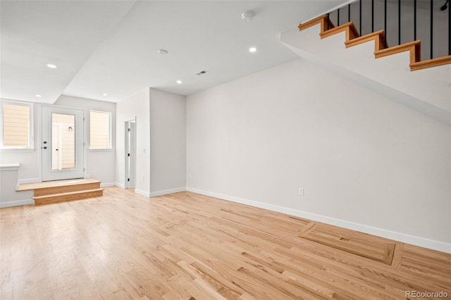unfurnished living room featuring light wood-style floors, baseboards, stairs, and recessed lighting