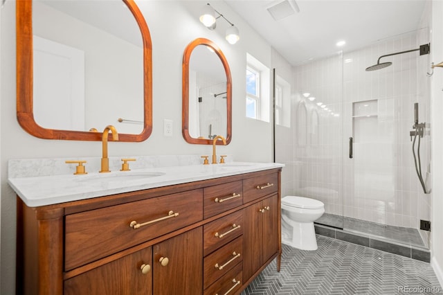 full bathroom featuring a sink, double vanity, toilet, and a shower stall