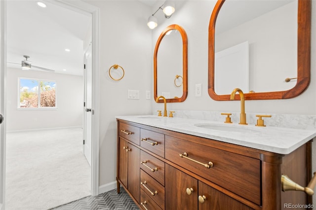 bathroom with baseboards, recessed lighting, double vanity, and a sink