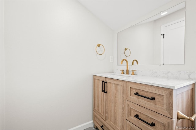 bathroom with vaulted ceiling, baseboards, and vanity