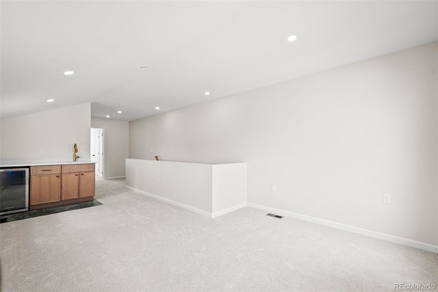 interior space featuring beverage cooler, light carpet, indoor wet bar, and baseboards