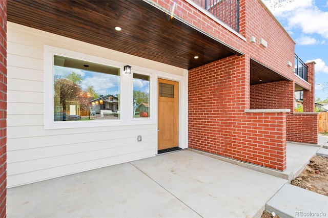 doorway to property featuring brick siding and a patio