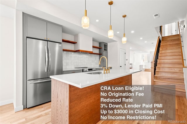 kitchen with stainless steel fridge, gray cabinetry, open shelves, light wood-style flooring, and decorative backsplash