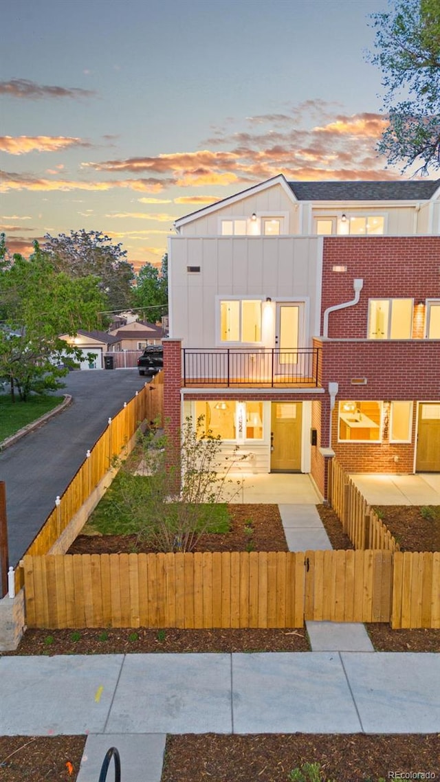 1052 N Knox Ct, Denver, CO 80204 - view of front of property featuring a balcony, a fenced front yard, and board and batten siding