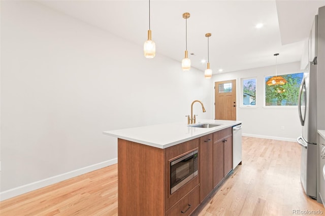 1052 N Knox Ct, Denver, CO 80204 - kitchen featuring appliances with stainless steel finishes, a sink, light wood-type flooring, brown cabinets, and recessed lighting