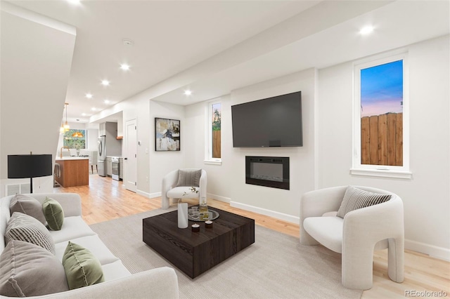 1052 N Knox Ct, Denver, CO 80204 - living room featuring light wood-type flooring, recessed lighting, a glass covered fireplace, and baseboards