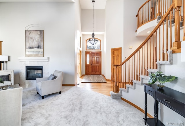 carpeted foyer with a tiled fireplace and a high ceiling