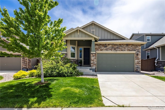 15392 W 49th Ave, Golden, CO 80403 - craftsman-style home with board and batten siding, a garage, a front lawn, concrete driveway, and stone siding