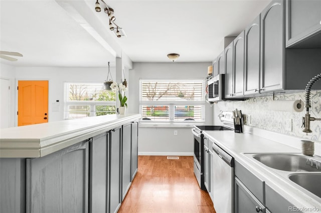 3202 S Dahlia St, Denver, CO 80222 - kitchen featuring stainless steel appliances, gray cabinetry, a sink, light wood finished floors, and light countertops