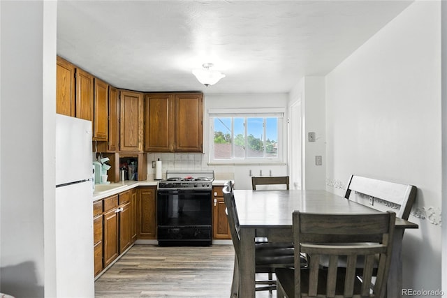 4505 W Gill Pl, Denver, CO 80219 - kitchen with range, freestanding refrigerator, light wood-style flooring, and brown cabinets