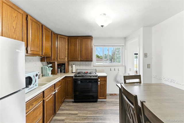 4505 W Gill Pl, Denver, CO 80219 - kitchen featuring stove, freestanding refrigerator, light wood-style floors, light countertops, and backsplash