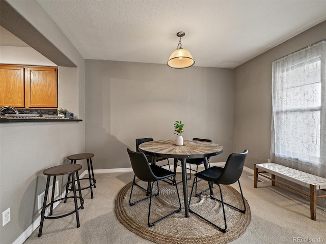 carpeted dining room featuring sink and a textured ceiling