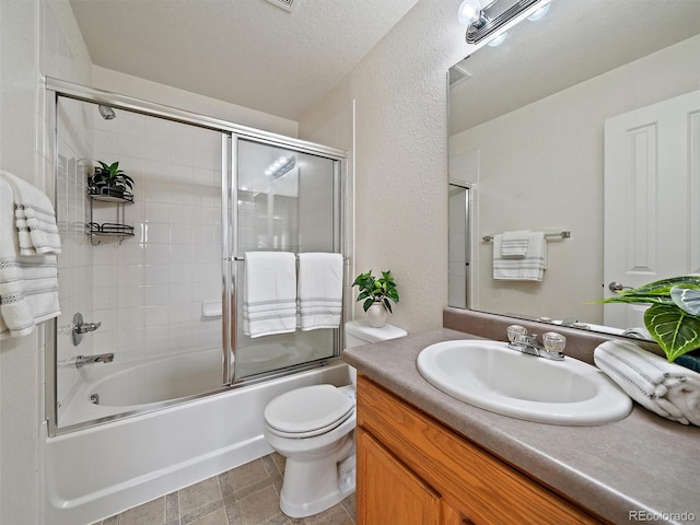 full bathroom with vanity, a textured ceiling, combined bath / shower with glass door, and toilet