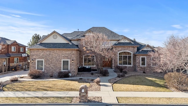 french country inspired facade featuring brick siding, a front lawn, and a shingled roof