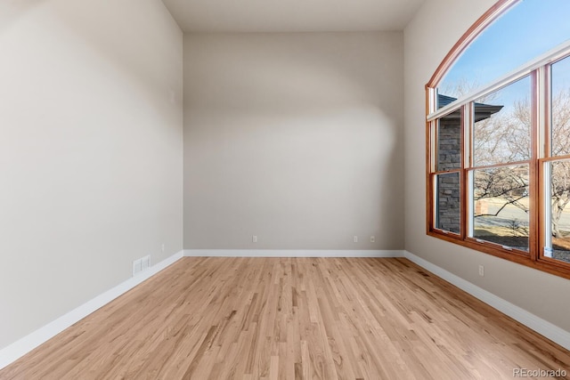 empty room featuring visible vents, baseboards, and light wood finished floors