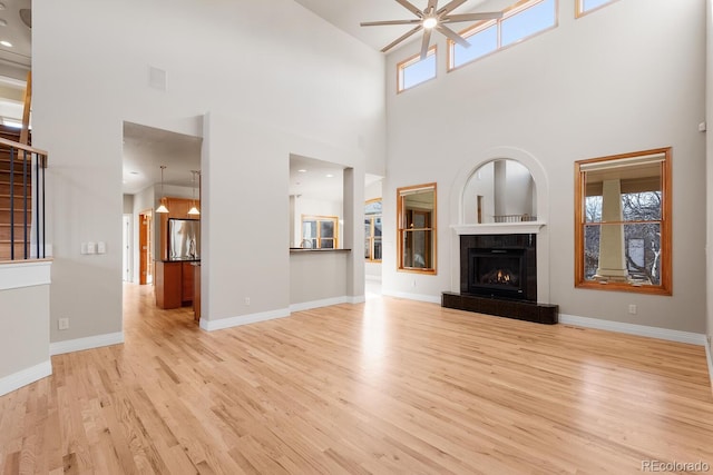 unfurnished living room with a healthy amount of sunlight, wood finished floors, baseboards, and ceiling fan