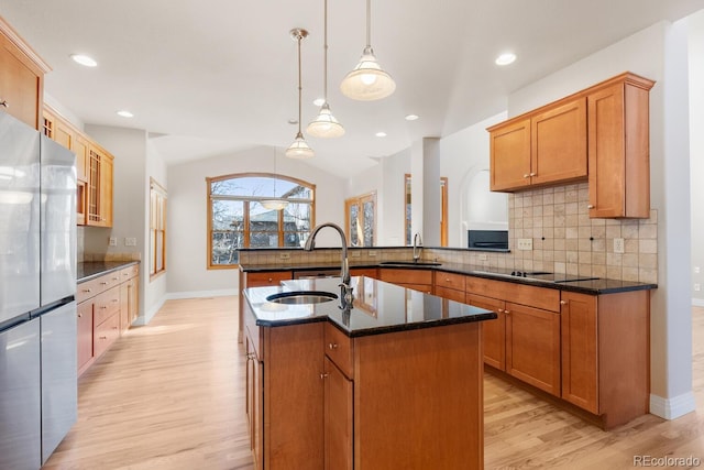 kitchen with tasteful backsplash, dark stone counters, freestanding refrigerator, and a sink