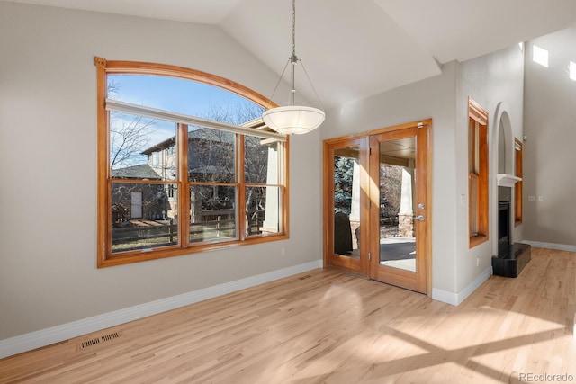 unfurnished dining area featuring visible vents, baseboards, lofted ceiling, and wood finished floors