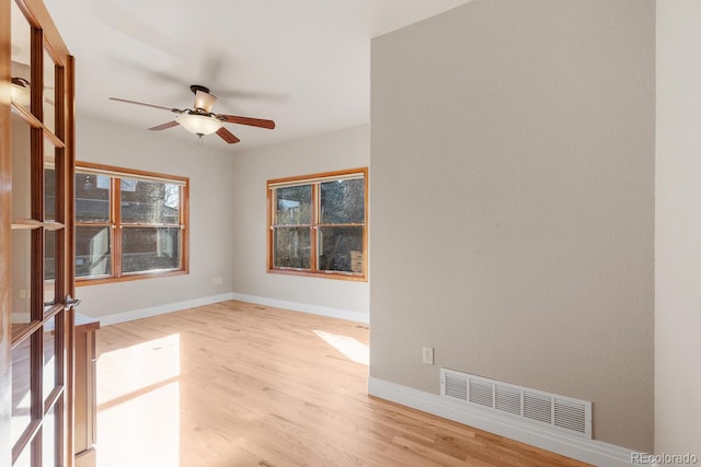 spare room with ceiling fan, baseboards, visible vents, and light wood-type flooring