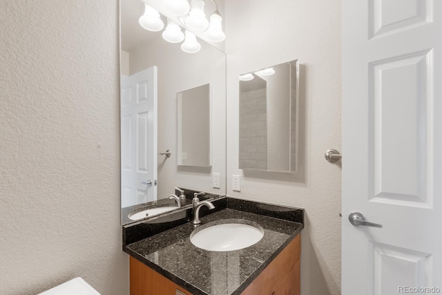 half bathroom with vanity and a textured wall