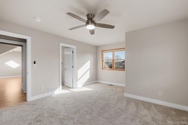 spare room with ceiling fan, baseboards, visible vents, and light carpet