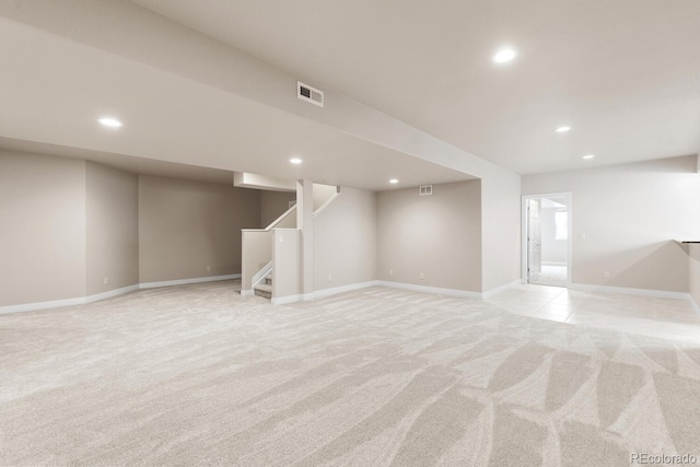 finished basement featuring visible vents, baseboards, recessed lighting, stairs, and light colored carpet