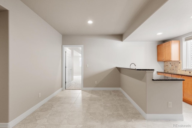 kitchen featuring tasteful backsplash, baseboards, recessed lighting, a peninsula, and a sink