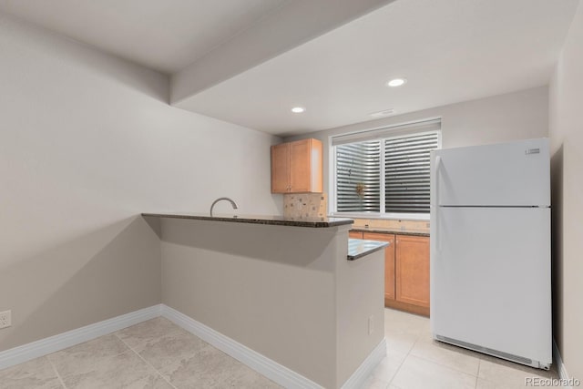 kitchen featuring backsplash, freestanding refrigerator, recessed lighting, a peninsula, and baseboards