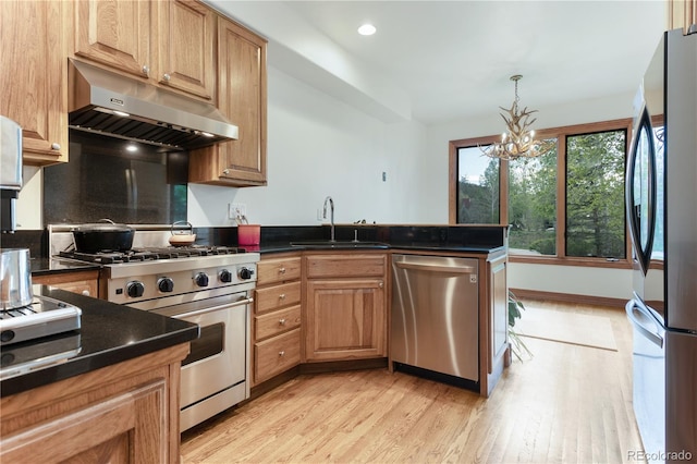 kitchen featuring light hardwood / wood-style flooring, a notable chandelier, appliances with stainless steel finishes, kitchen peninsula, and sink