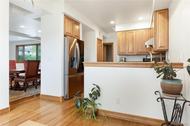 kitchen with light hardwood / wood-style flooring, kitchen peninsula, and stainless steel refrigerator with ice dispenser