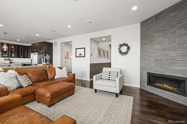 11046 Pastel Pt, Parker, CO 80134 - living room featuring recessed lighting, baseboards, an accent wall, dark wood-style flooring, and a tiled fireplace
