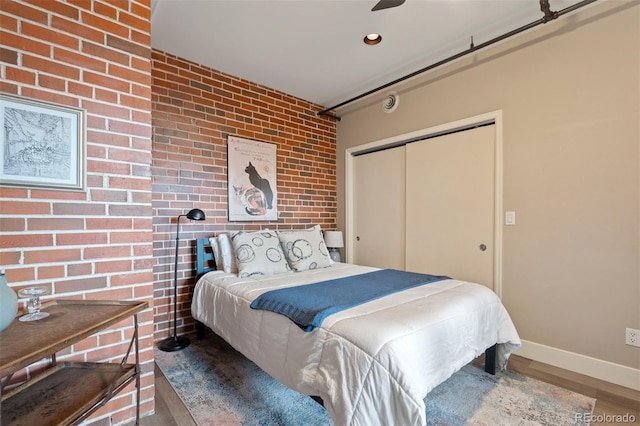1515 N Ogden St Unit 7, Denver, CO 80218 - bedroom featuring a closet, baseboards, wood finished floors, and brick wall