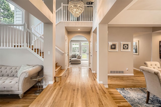 9962 Stratford Ln, Highlands Ranch, CO 80126 - entrance foyer with light wood finished floors, a chandelier, stairs, arched walkways, and a high ceiling