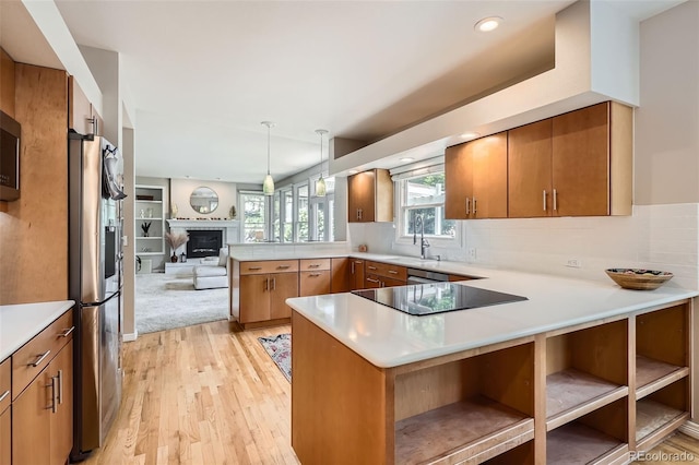 9962 Stratford Ln, Highlands Ranch, CO 80126 - kitchen with a peninsula, stainless steel appliances, light countertops, light wood-style floors, and brown cabinetry