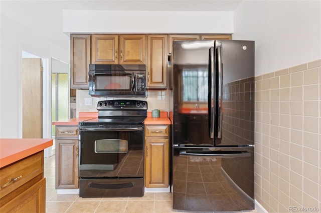 8484 E Radcliff Ave, Denver, CO 80237 - kitchen with black appliances, light countertops, brown cabinetry, light tile patterned floors, and tile walls
