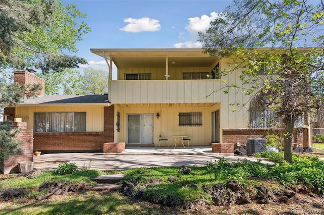 8484 E Radcliff Ave, Denver, CO 80237 - back of house with a patio, brick siding, board and batten siding, and a chimney