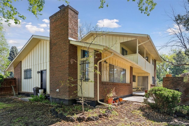 8484 E Radcliff Ave, Denver, CO 80237 - back of house featuring a balcony, board and batten siding, a chimney, and brick siding